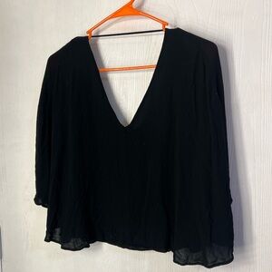 Sleeveless black womans top with a deep V-neckline and sheer sleeves.